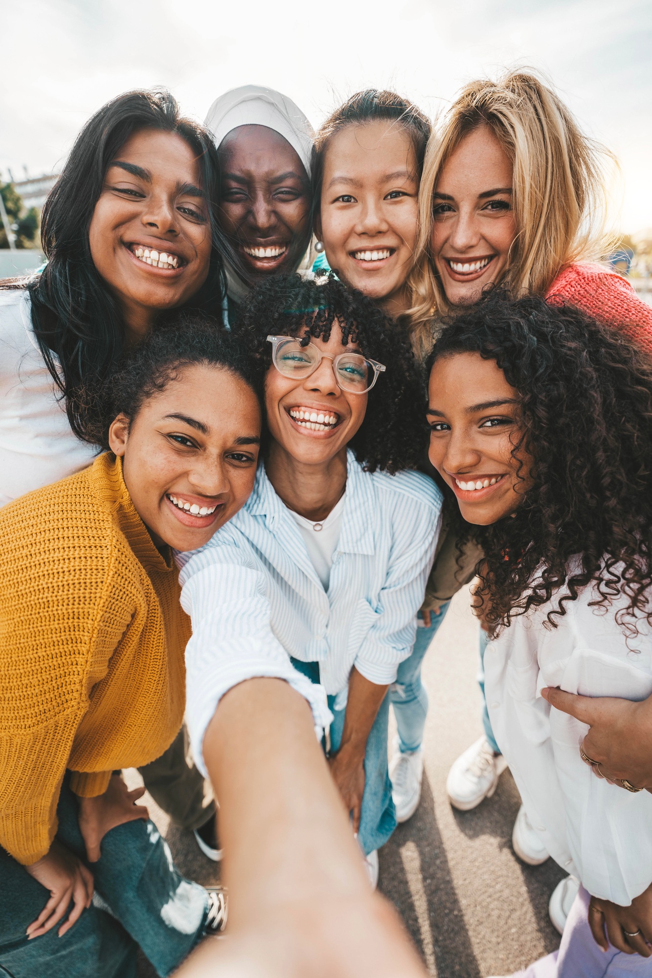 Multicultural young women taking selfie with smart mobile phone device outside